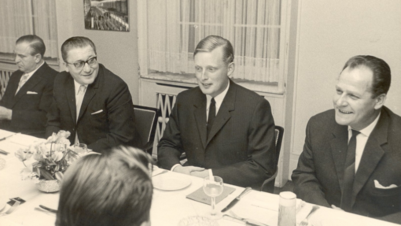 Altes Foto der damaligen Geschäftsführung, in Anzügen gekleidet, an einem Tisch