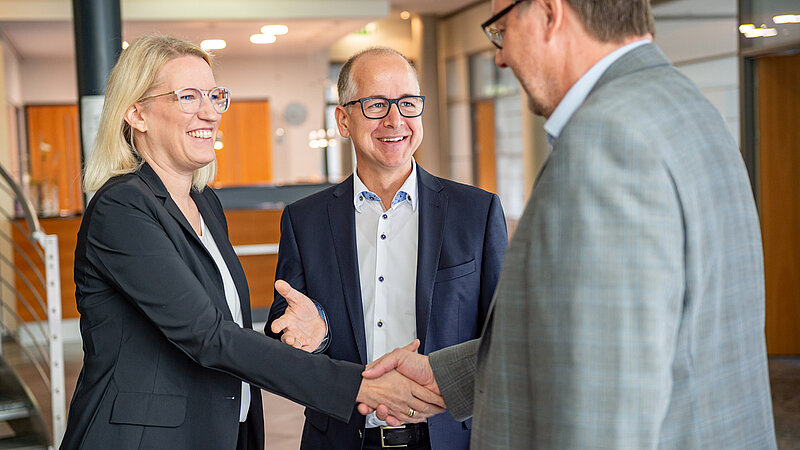 Die Geschäftsleitung reicht einem Herrn partnerschaftlich die Hand