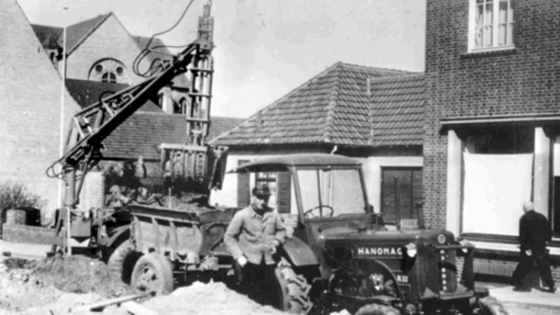 Altes Schwarz-Weiß-Foto von einem Mann vor einem Bagger